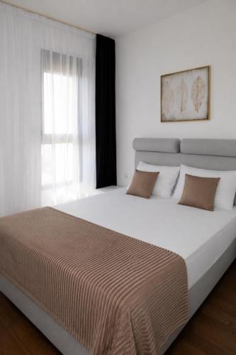 a large bed in a white room with a window at Celuga sea view apartments in Bar