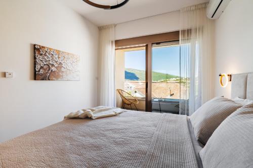 a white bedroom with a bed and a large window at Maria Premium BELLA VISTA in Baošići