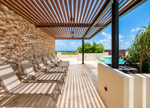 a patio with lounge chairs and a brick wall at Syrena Luxury Caribbean - Heart of Playa del Carmen - Sea Views in Playa del Carmen