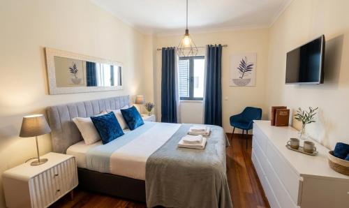 a bedroom with a large bed with blue pillows at To Be Apartments in Bobadela
