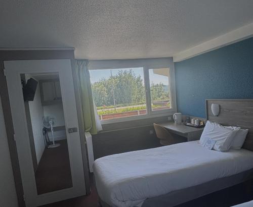a hotel room with a bed and a window at Kyriad Cambrai in Cambrai