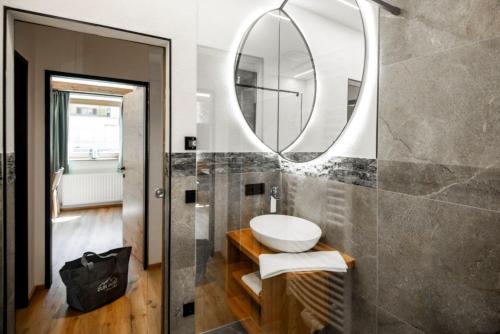 a bathroom with a sink and a mirror at AlpinSpa zur Post Apartment - Bergbahn im Sommer 2026 inklusive in Bad Gastein