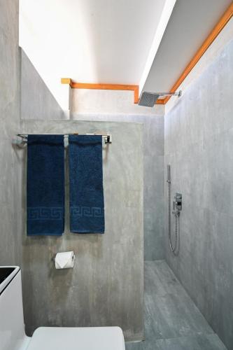 a bathroom with a shower with a toilet and blue towels at Dive and Sleep - All Inclusive Diving Guesthouse - 3 Dives per day in Maamigili