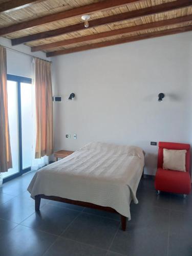 a bedroom with a bed and a red chair at Casa Berenice in Zorritos