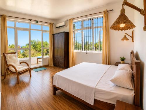 a bedroom with a bed and a chair and a window at Suntoo Villa Wind & Kitesurf Accommodation in La Gaulette