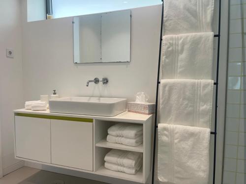 a bathroom with a sink and a mirror and towels at Ria & Mar Collection I in Aveiro