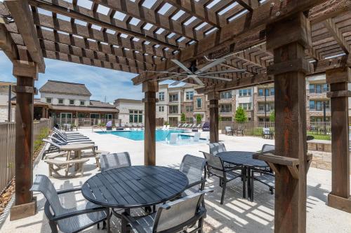a patio with tables and chairs and a pool at Luxury McKinney Resort Stay Near Universal Kids with Pool & Gym in McKinney
