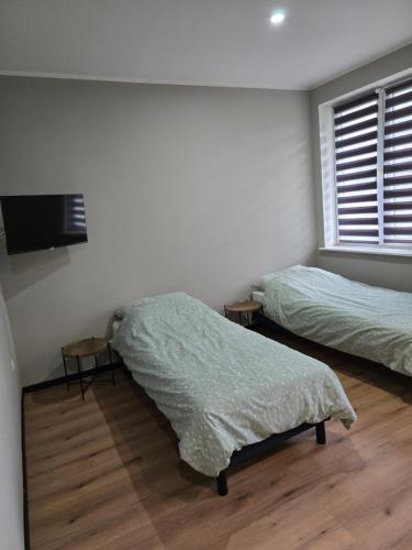 a bedroom with two beds and a flat screen tv at Apartament 1 w Leśnym Zaciszu in Czertyń