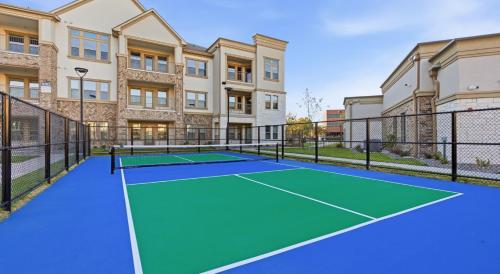 a tennis court in front of a building at Luxury McKinney Resort Stay Near Universal Kids with Pool & Gym in McKinney