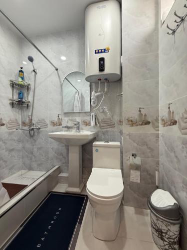 a bathroom with a white toilet and a sink at Hotel Bogatt in Dushanbe