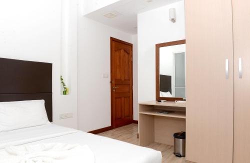 a bedroom with a bed and a sink and a mirror at Express Inn at Hulhumale in Hulhumale