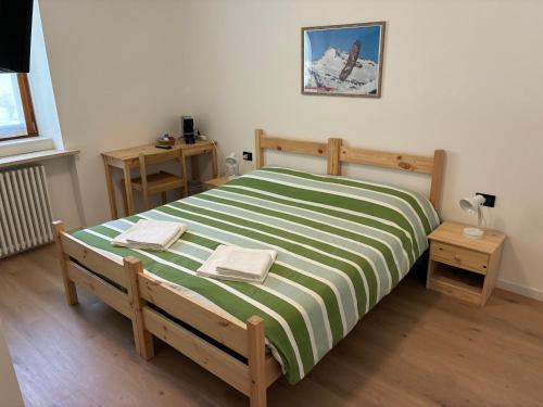 a bedroom with a green and white bed with two tables at Affittacamere Penasa in Rabbi