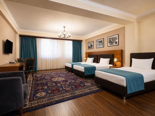 a hotel room with two beds and a desk at Cathedral Plaza Hotel in Gyumri