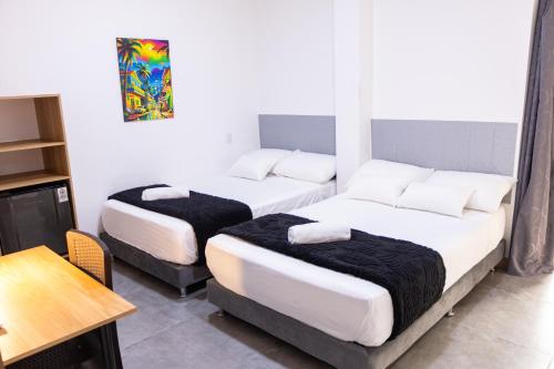 two beds in a small room with a table and a table at Komfort House Premium in Medellín