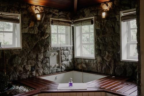 a stone bathroom with a sink and windows at Villa Don in Petrópolis