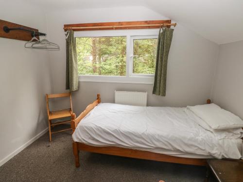 a bedroom with a bed and a window and a chair at Cabin No 2 - Salt and Fern Cabins in Port Talbot
