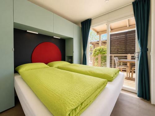 a bedroom with two beds with green sheets at Camping Al Porto - Mini Glamping & Mobile Homes in Nago-Torbole