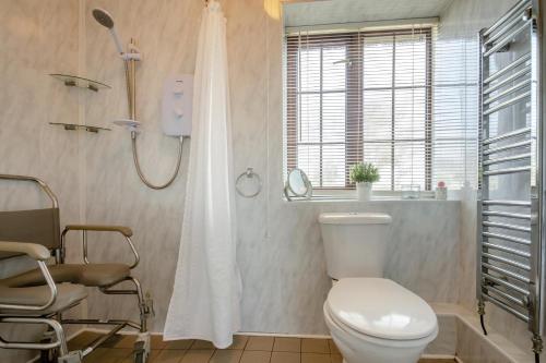 a bathroom with a white toilet and a shower at 3 Bed in Llanfairpwll oc-22999 in Llanfairpwllgwyngyll