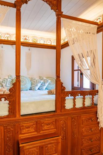 a wooden canopy bed with a mirror in a room at Lithos House in Avlóna
