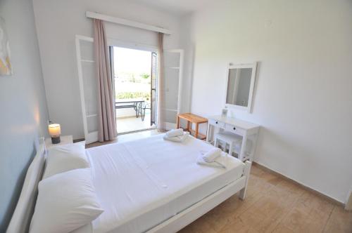 a white bedroom with a bed and a window at Alexandra On The Beach in (( Litherés ))