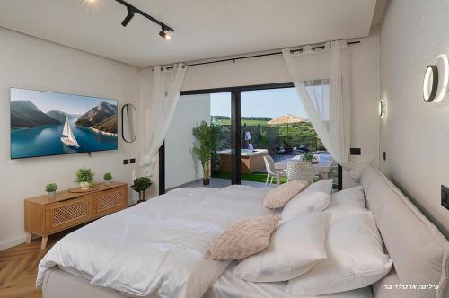 a bedroom with a large white bed and a large window at Sagit luxury suites in Elqosh