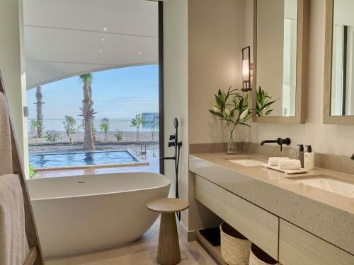 a bathroom with a tub and a sink and a mirror at Hawar Resort By Mantis in Hawar Island