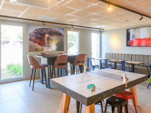 a restaurant with tables and chairs with an umbrella on the wall at Ibis Budget La Rochelle Puilboreau in Puilboreau