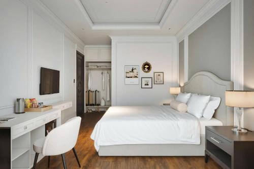 a white bedroom with a white bed and a desk at The Manor Hotel in Nam Ðịnh