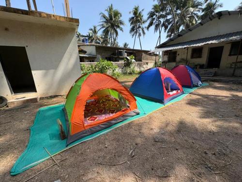three tents are set up outside of a house at Sea front tent house in Murud