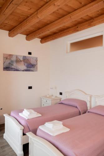 two white beds in a room with wooden ceilings at locazione turistica PetitePomme in Borso del Grappa