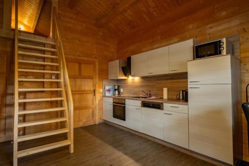 a kitchen with white cabinets and a staircase in a cabin at Waldsiedlung - Haus 9 in Senftenberg