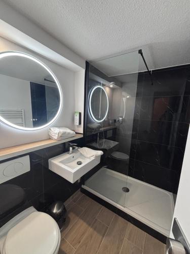 a bathroom with a sink and a glass shower at Kyriad Cambrai in Cambrai