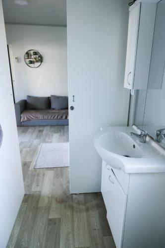 a white bathroom with a sink and a couch at Mobile Home ADRIA in Privlaka