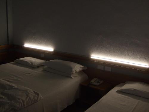 two beds in a room with lights on the wall at Hotel Canturio in Cantù