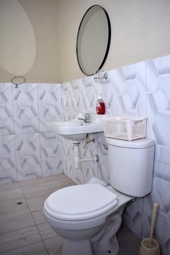 a white bathroom with a toilet and a sink at Los Portales de Yungar Ecolodge Huaraz in Carhuaz