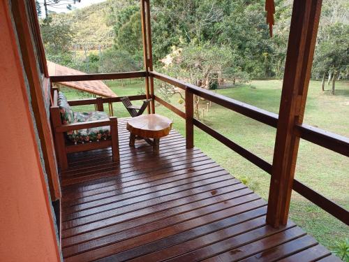 a wooden porch with a bench and a table on it at Pousada Recanto Lajinha - Chalé Amor Eterno in Visconde De Maua