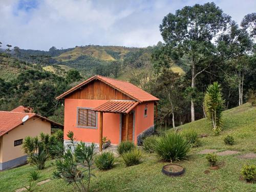 a house on a hill with a mountain in the background at Pousada Recanto Lajinha - Chalé Amor Eterno in Visconde De Maua