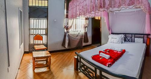 a bedroom with a bed with red pillows on it at Marindo Lodge Moshi in Moshi