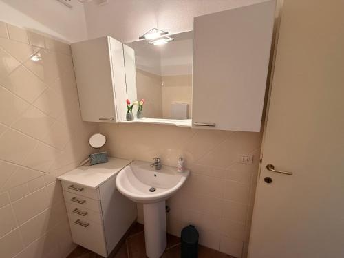 a white bathroom with a sink and a mirror at Perla di Lago Maggiore in Oggebbio