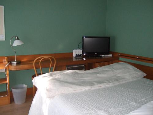 a bedroom with a bed and a television on a desk at Hotel Canturio in Cantù