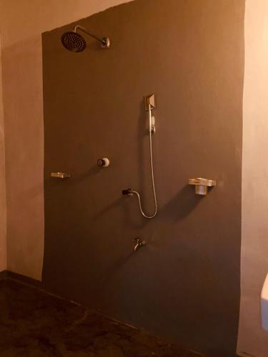 a bathroom with a shower with a hose on the wall at KR Villa in Arugam Bay
