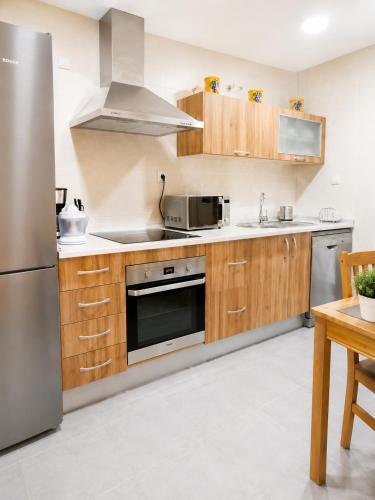 a kitchen with wooden cabinets and a stainless steel refrigerator at LyriosHomes Beach Costa Ballena in Chipiona