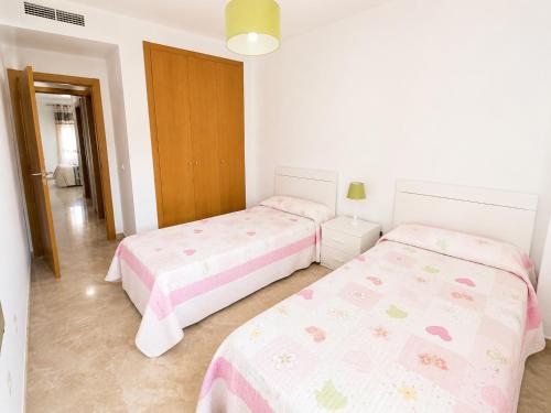two beds in a white room with pink sheets at LyriosHomes Beach Costa Ballena in Chipiona