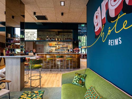 a bar with a green couch in a restaurant at greet Hotel Reims Tinqueux in Reims