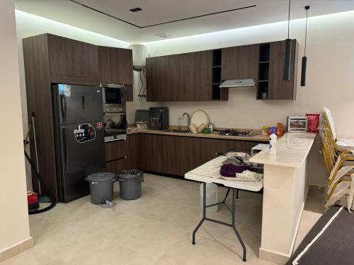 a kitchen with wooden cabinets and a table and a refrigerator at شاليه مرزوقة in Buraydah