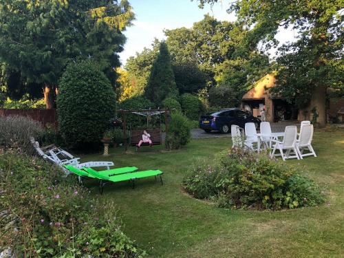 a garden with white chairs and a green table and chairs at Charming loft sleeps up to 9 with spa option in Bournemouth