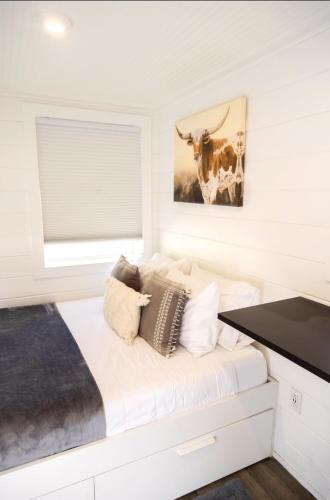 a white bedroom with a cow painting on the wall at NEW! Cozy Container Home at Cliffside #2 in Orderville