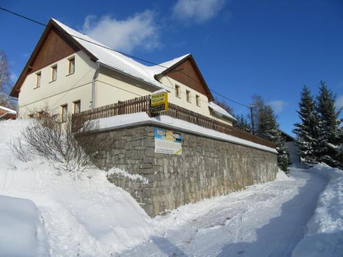 a house with a stone wall in the snow at Apartmány Yellow in Horní Maršov