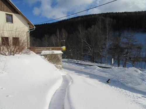 a road covered in snow next to a house at Apartmány Yellow in Horní Maršov