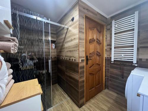 a bathroom with a shower and a wooden door at Apartman Tri srca Zlatar in Nova Varoš